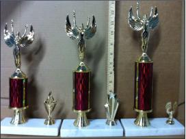 Three tophies ranging in size. Victory trophies on top of a post with a side trim decoration.